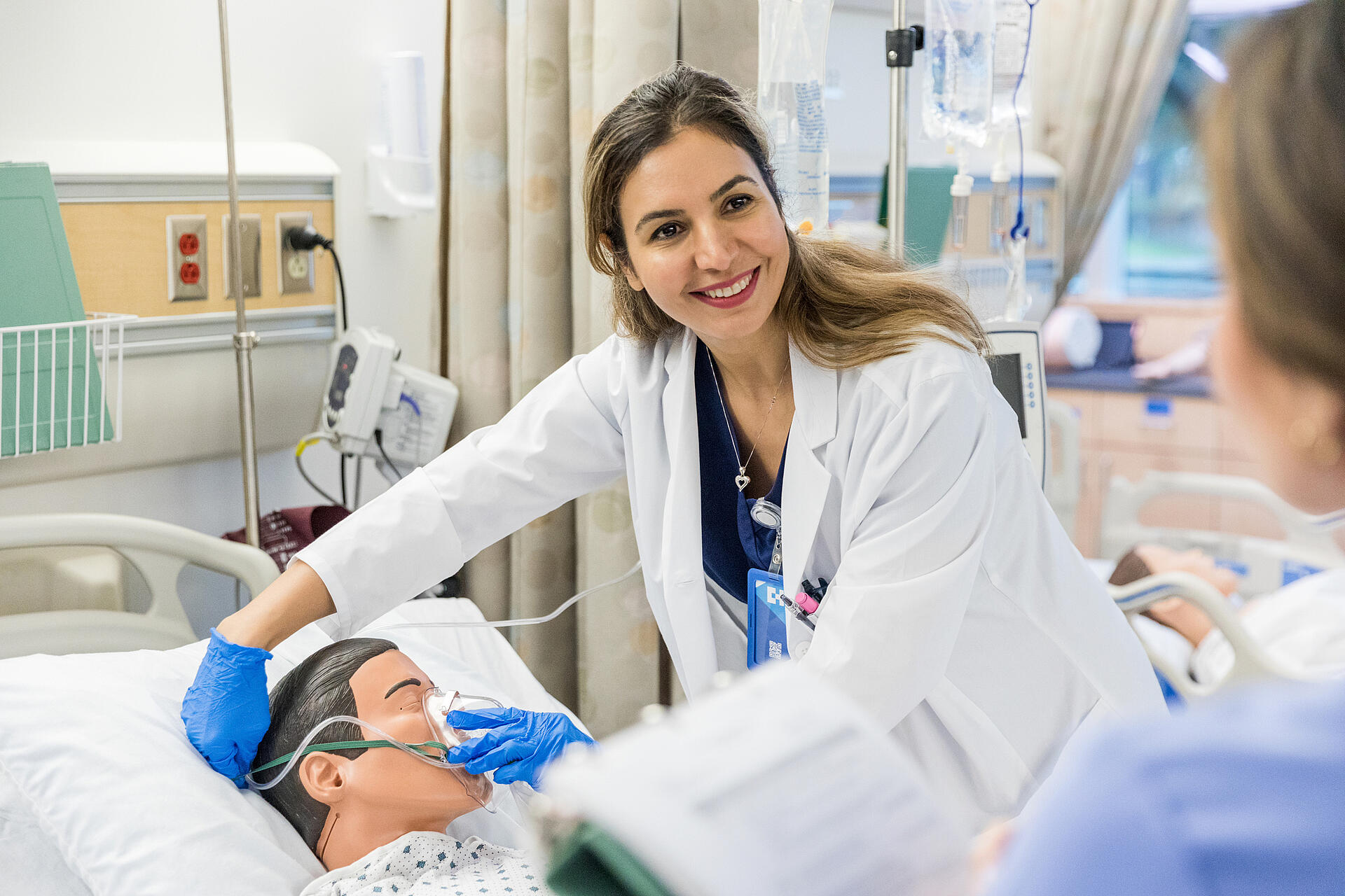 Krankenhaustrainer lächelt als Praktikant, der eine Frage zur Sauerstoffmaske stellt